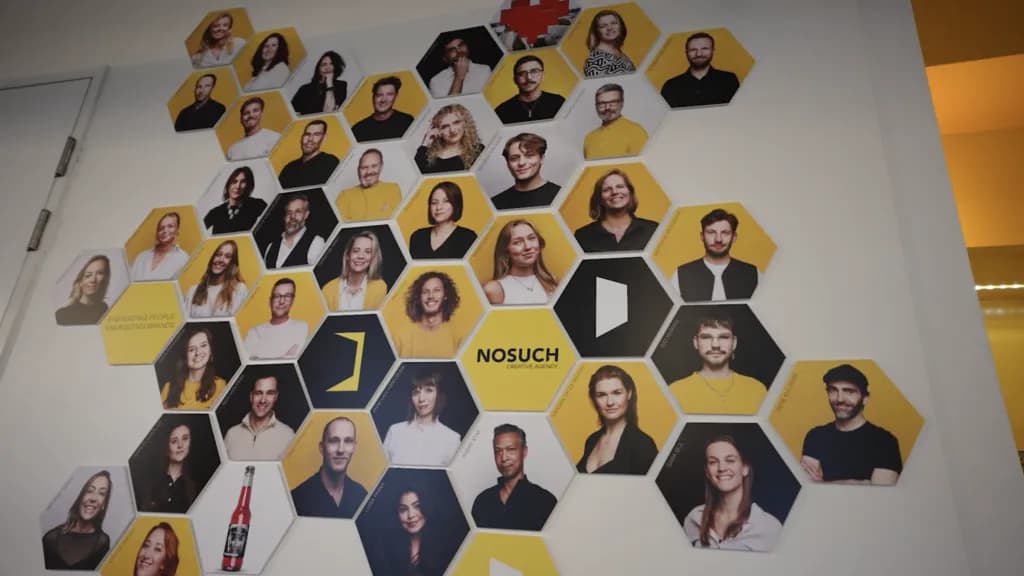 Teamwand van NOSUCH Creative Agency met portretfoto's in honingraatvorm op kantoor, als beeld bij de NOSUCH case