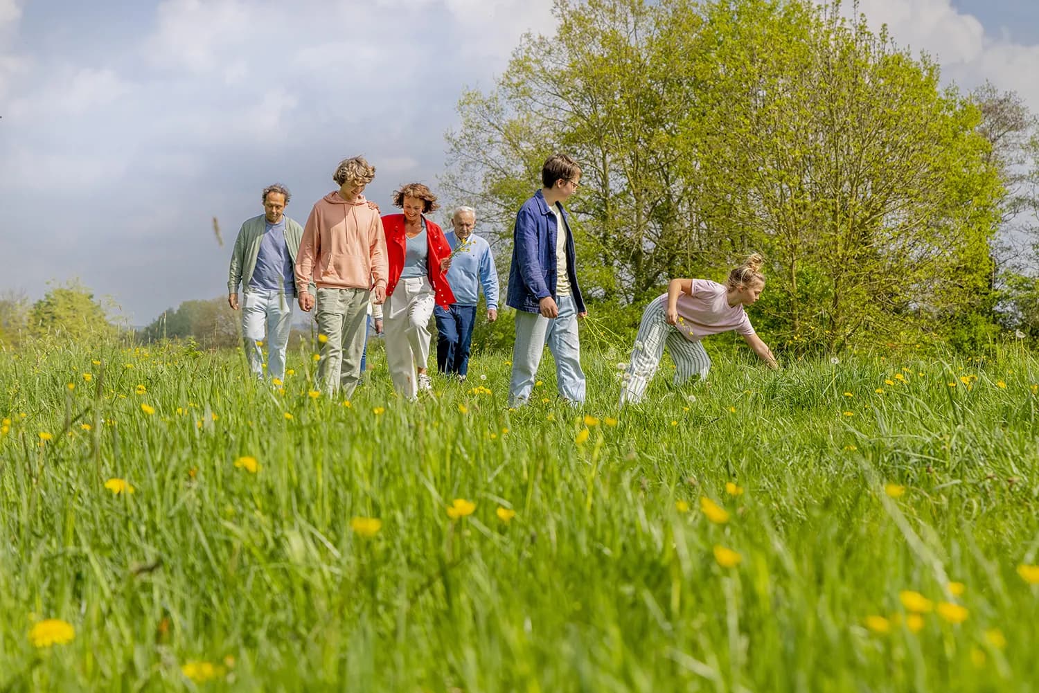 Familie wandelt samen door een groen weiland met wilde bloemen, als beeld bij de Pantein zorgorganisatie case